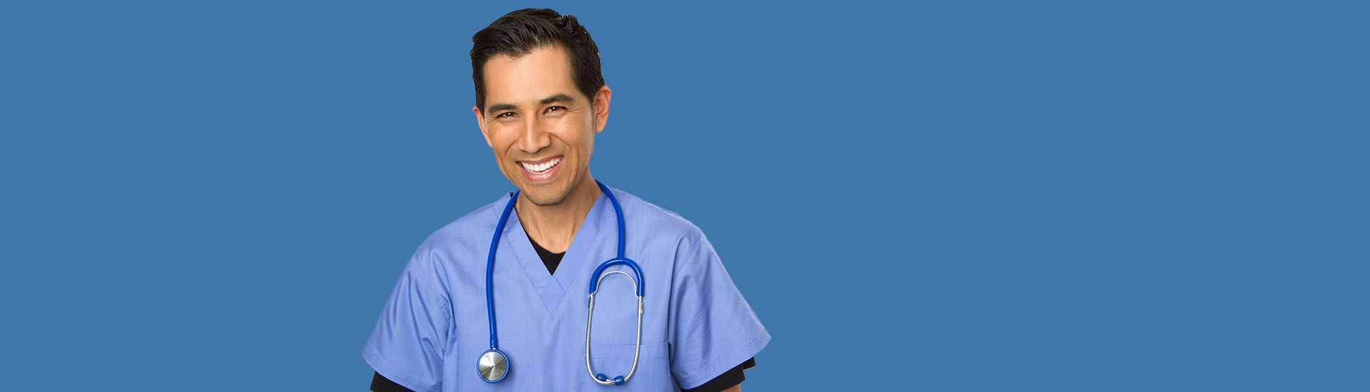 Smiling doctor in blue scrubs and stethoscope.