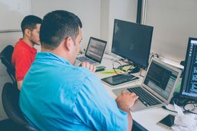 Men working on computers in office setting.