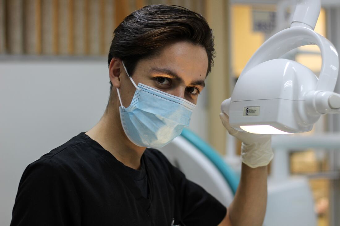 Dentist with mask adjusting dental light.