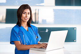 Nurse using a laptop in medical office.
