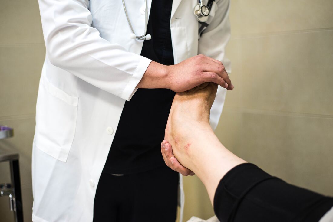 Doctor examining patient's foot in clinic.