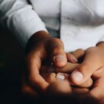 Hands gently holding each other in support.