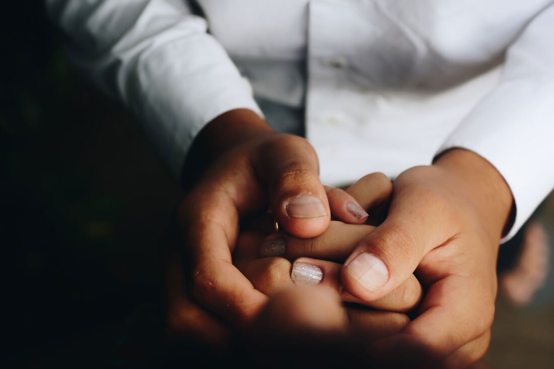 Hands gently holding each other in support.
