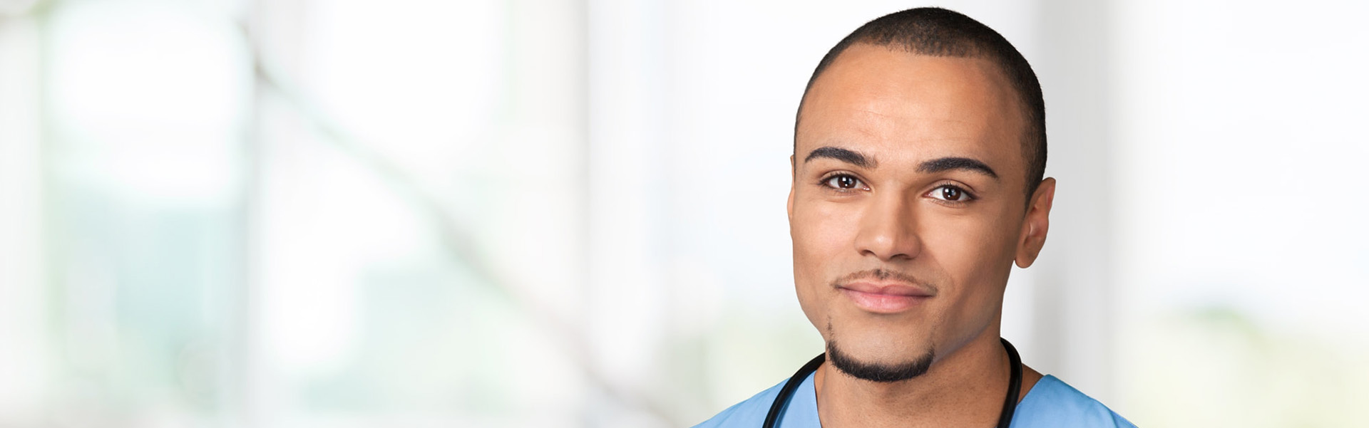 Smiling healthcare worker in blue scrubs.