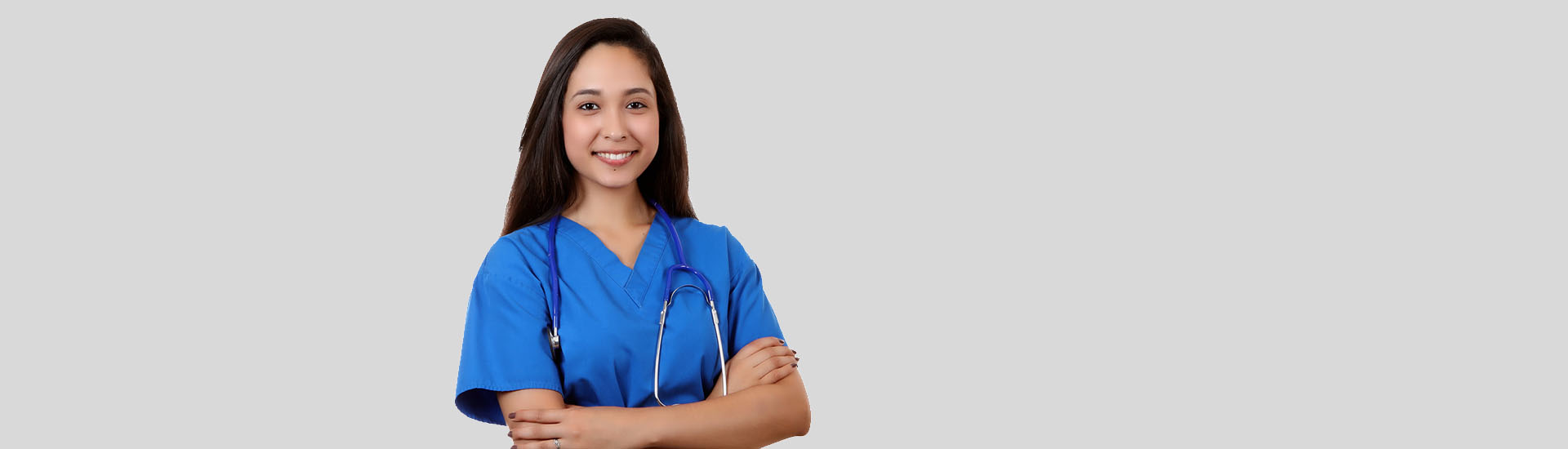 Smiling nurse in blue scrubs with stethoscope.