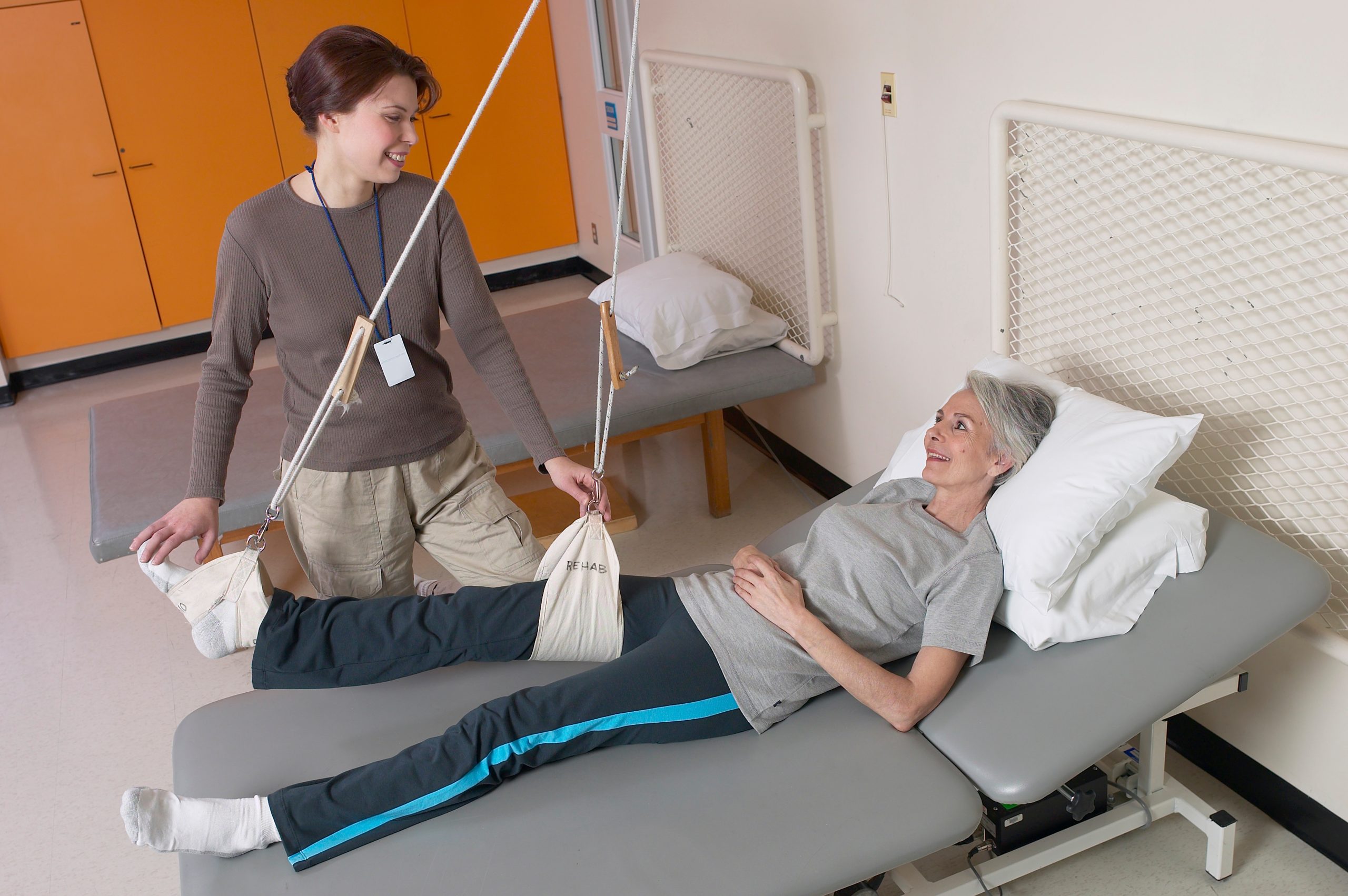 Therapist assists patient with leg exercises.