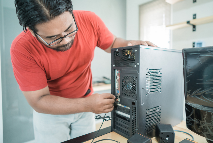 Man connecting cables to a computer tower.