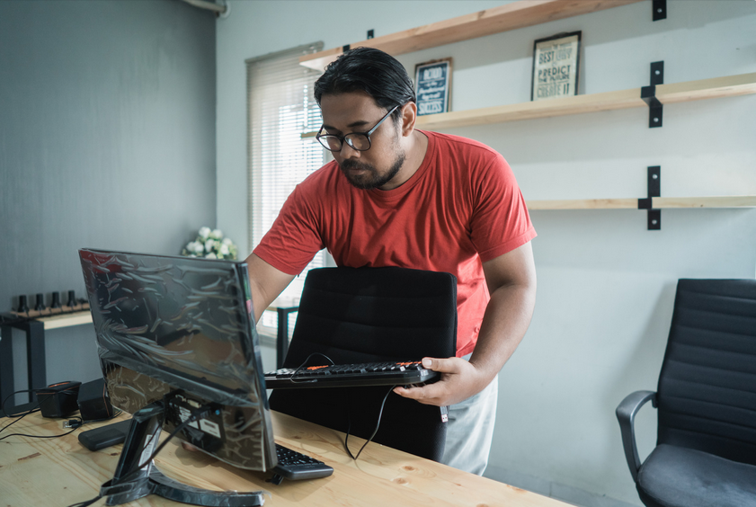 Man setting up computer in office space.