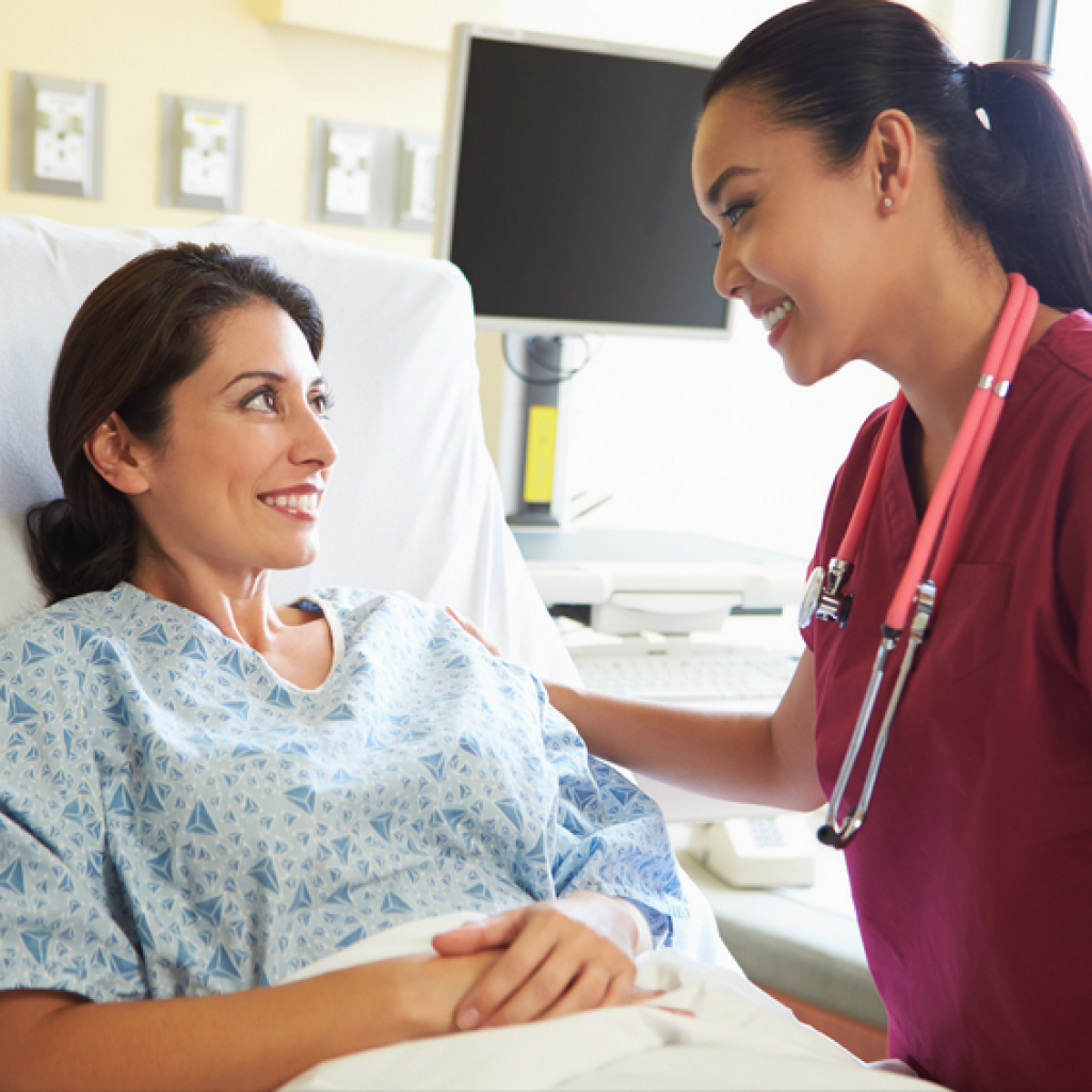 Nurse comforting patient in hospital bed.