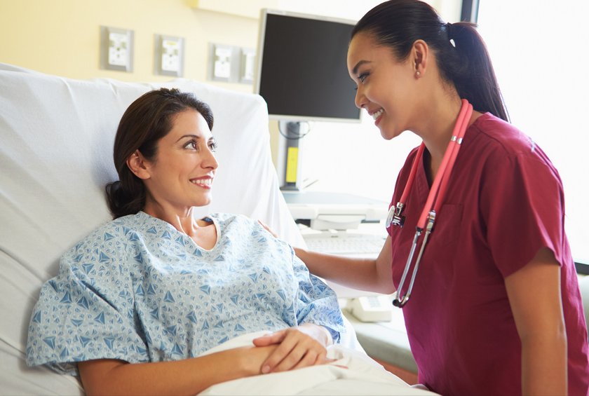 Nurse comforting patient in hospital bed.