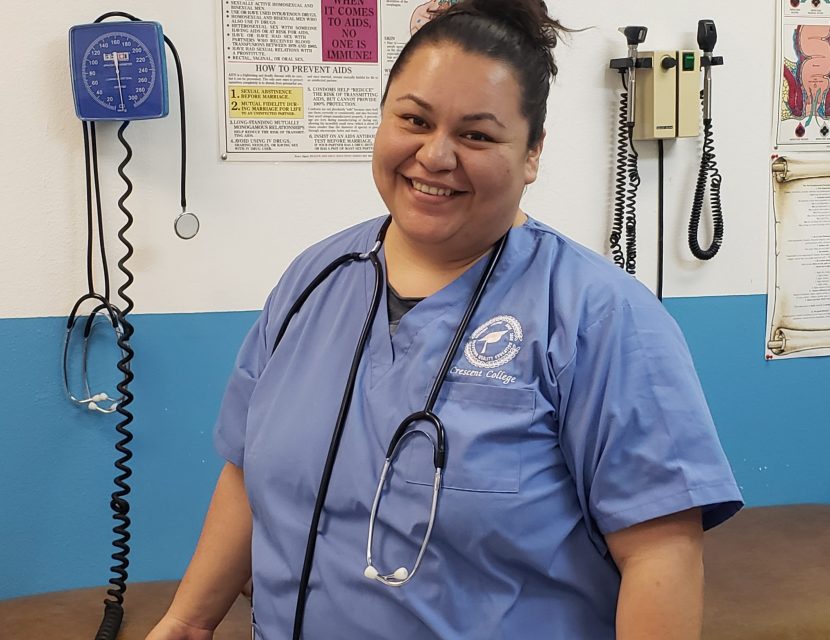 Smiling nurse in blue scrubs, stethoscope.
