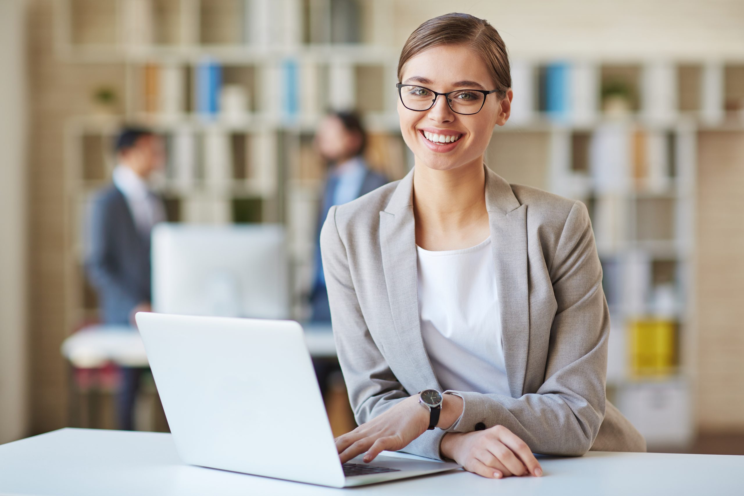 Smiling woman in office with laptop.